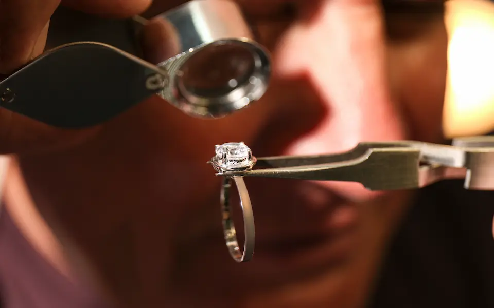 Diamond ring being appraised with the help of a magnifying glass